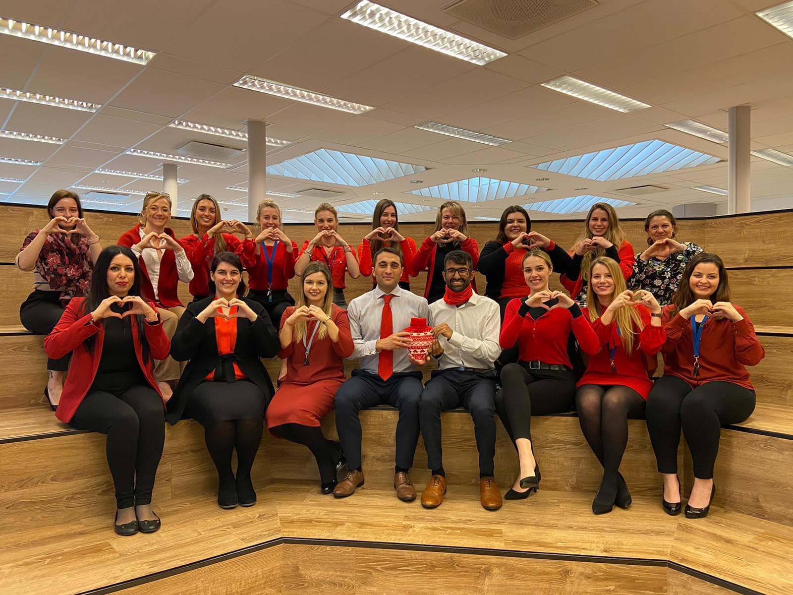 Volunteers dressed in red making heart shapes with their hands on Wear Red Day